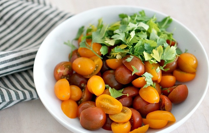 1. Этап. Салат с курицей и запеченным нутом: 6. Вымойте, обсушите и нарежьте пополам помидорки. Измельчите зелень.