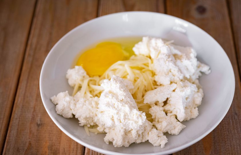 1. Этап. Хачапури из слоеного теста с сыром и творогом: В просторную миску выложите творог, к нему натрите на крупную терку сыр, вбейте яйцо.