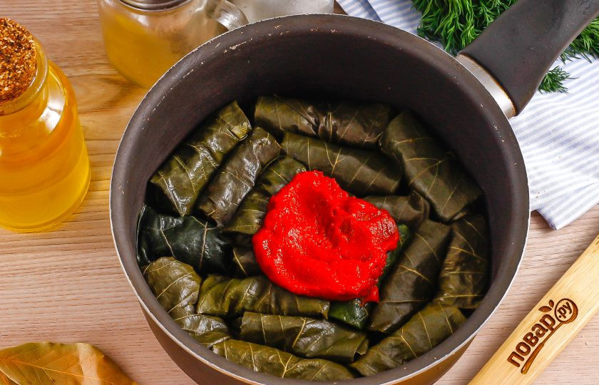 1. Этап. Сармале: Выложите их в казан или ковш с антипригарным дном. Добавьте туда же томатную пасту и 1 стакан горячей воды.