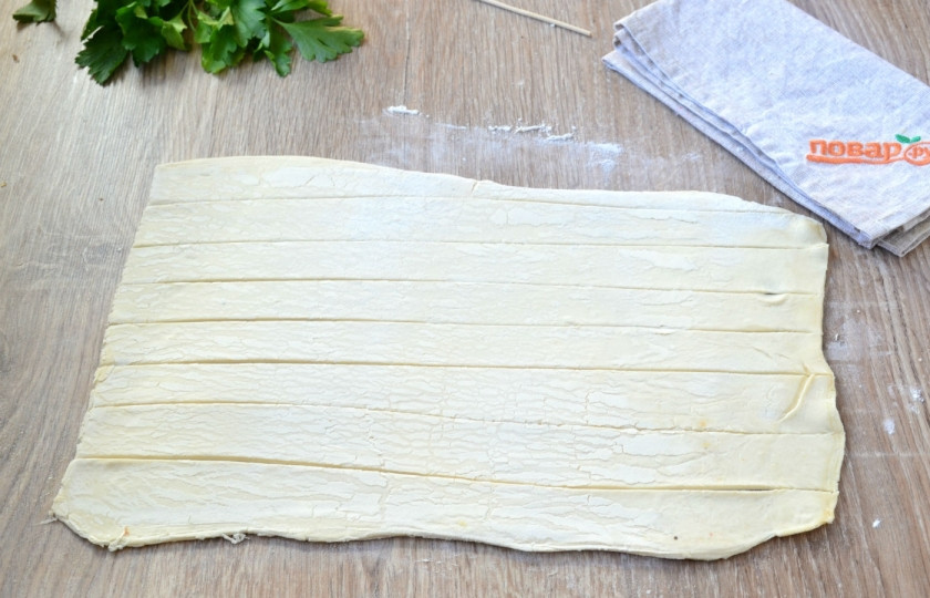 1. Этап. Сосиски в тесте на шпажках: Тесто раскатайте толщиной около 2 мм, порежьте на полоски шириной 2-3 см.