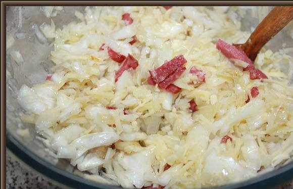 1. Этап. Шарлотка с капустой в мультиварке: Капусту мелко порежьте, посолите и поперчите. Затем, для мягкости, помните ее руками. Смешайте с обжаренным луком и колбасой. Так же добавьте натертый на терку сыр.