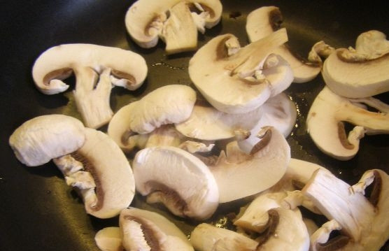 1. Этап. Салат с пекинской капустой и свежими грибами: Разогрейте масло на сильном огне в сковороде. Обжарьте в нём 4 минуты шампиньоны, помешивая.