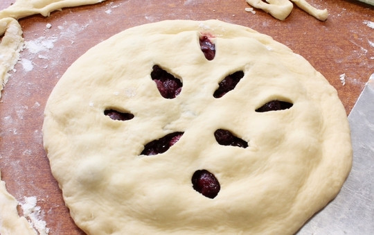 1. Этап. Осетинский пирог Балджин: Накройте вишню второй лепешкой. Прорежьте отверстия произвольной формы и скрепите пальцами стыки теста по окружности. Выпекайте ягодный пирог при температуре 180 градусов, предварительно раскалив духовку, примерно 25-30 минут.