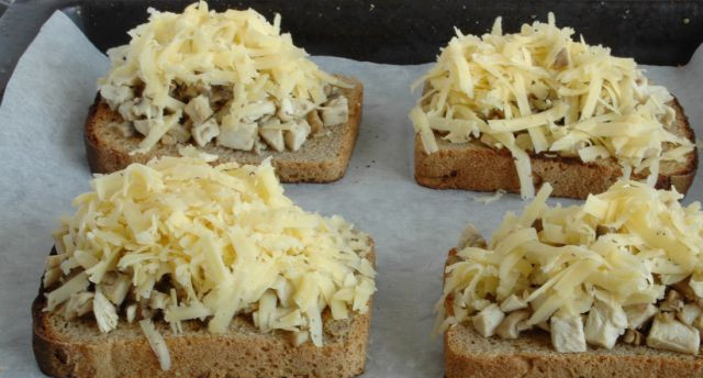 1. Этап. Гренки с грибами: Подрумяненный хлеб выложить на противень, сверху - грибную массу (я ее не солю, т.к в принципе мало использую соль, к тому же нужно учитывать соленость сыра). Посыпать заготовки тертым сыром.