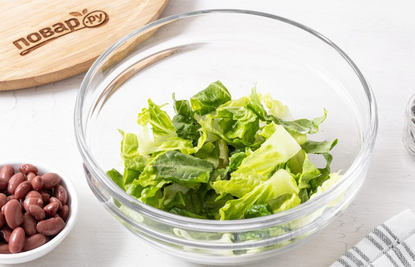 1. Этап. Салат с фасолью и ананасом: Листья ромэна нарежьте широкими полосами. Переложите в глубокую миску.