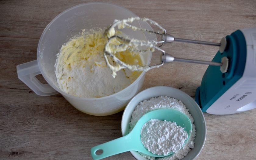 1. Этап. Пирожное Корзиночка с масляным кремом: Для приготовления масляного крема сначала взбейте сливочное масло комнатной температуры до пышности. Затем постепенно добавьте просеянную сахарную пудру и ванильный сахар. Взбивайте до однородности.