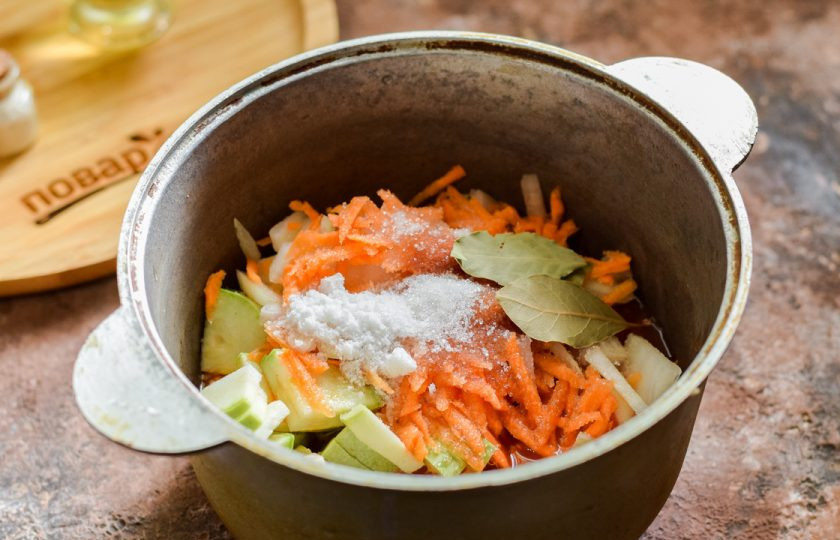 1. Этап. Закуска Казацкая на зиму: Всыпьте соль и сахар, добавьте лавровый лист. Прикройте кастрюлю крышкой и тушите кабачки 35 минут.