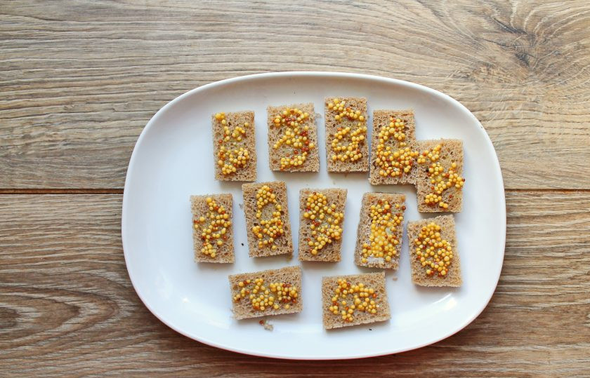 1. Этап. Канапе с селедкой и черным хлебом на шпажках: Каждый кусочек хлеба смажьте горчицей.