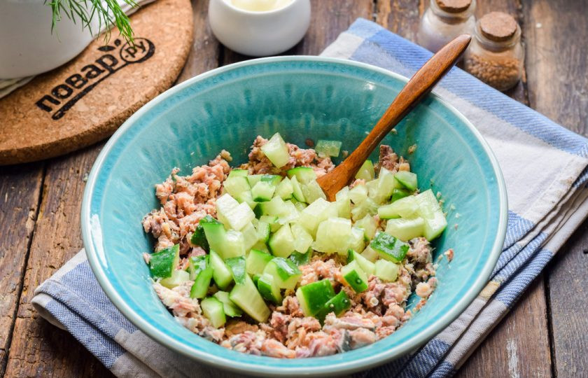 1. Этап. Салат из консервированной сайры: Свежий огурец ополосните и просушите, нарежьте небольшими кубиками и добавьте к рыбе.