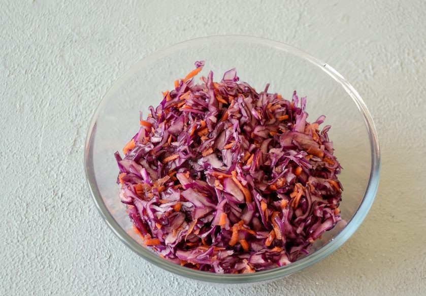 1. Этап. Квашеная краснокочанная капуста: В большой миске соедините их вместе. Руками начните сжимать капусту до образования сока, затем посолите и перемешайте.