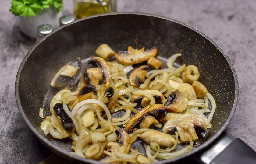 1. Этап. Жаркое из свинины с грибами и баклажанами: Грибы нарежьте крупными пластинами, очищенную луковицу нарежьте полукольцами. В сковороде разогрейте немного масла, выложите грибы и лук, жарьте несколько минут.