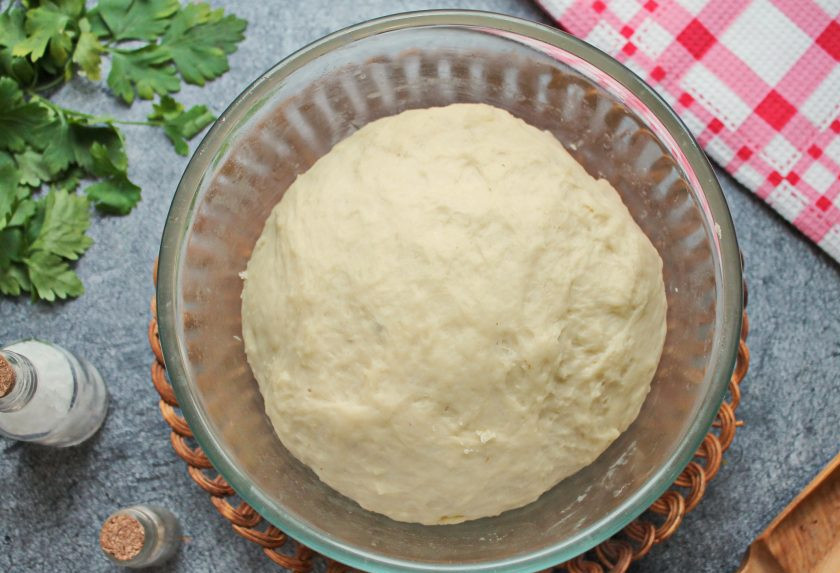 1. Этап. Пирожки с мясом и картошкой в духовке: Муку просейте, частями добавьте ее в жидкую часть и замесите мягкое, не липкое тесто. Сформируйте тесто в шар, выложите в глубокую миску, смазанную растительным маслом. Миску с тестом накройте и поставьте в теплое место на 40-60 минут для подъема в 2-2.5 раза.