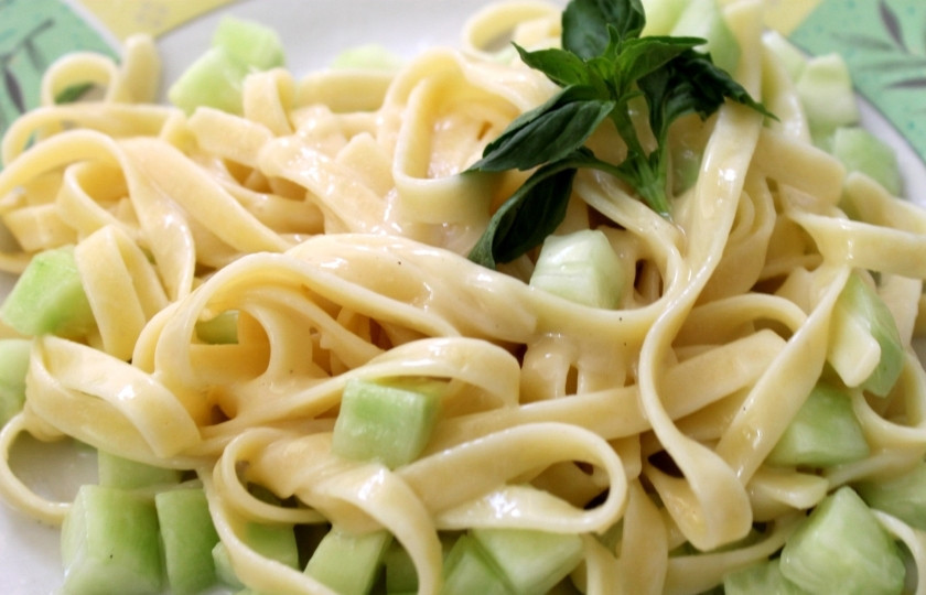 1. Этап. Макароны с огурцами: В маленькой кастрюле растопите сливочное масло. Добавьте жирных сливок, тёртого сыра Пармезан и давленный чеснок. Помешайте. Варите около пяти минут. Полейте сливочным соусом макароны с огурцом. Помешайте. Перед подачей украсьте зеленью.