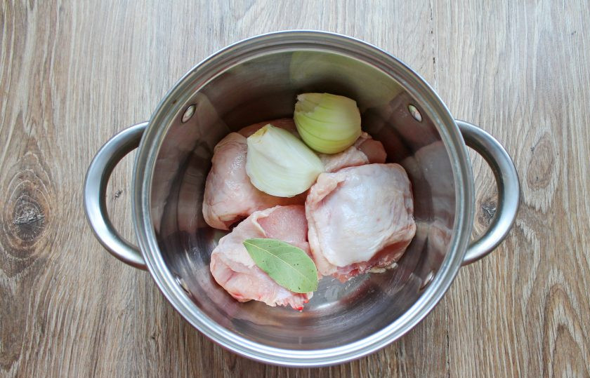 1. Этап. Черный рис с курицей: Курицу промойте и выложите в кастрюлю. Добавьте лавровый лист и порезанную, очищенную луковицу.