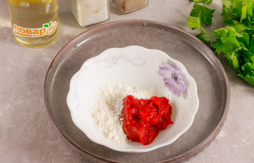 1. Этап. Подлива из лука, моркови, сладкого перца и томата: В пиалу выложите томатную пасту и всыпьте муку. Влейте холодную воду и перемешайте все, чтобы мука не образовала комочки.