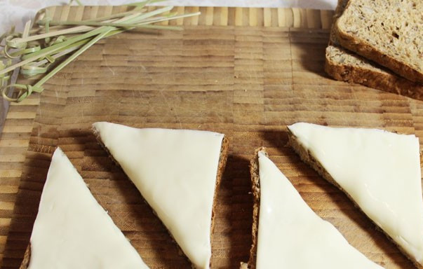 1. Этап. Бутерброды с килькой: Выкладываем на них по ломтику плавленного сыра разрезаем хлеб по диагонали на две части.