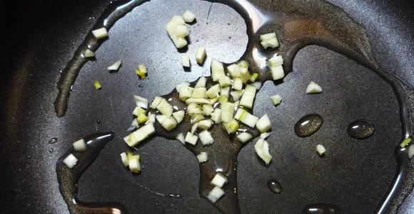 1. Этап. Салат из брокколи и шампиньонов: Ставим сковороду на огонь. Смазываем растительным маслом. Чистим и режем мелко чеснок. Обжариваем его на сковородке пару минут.