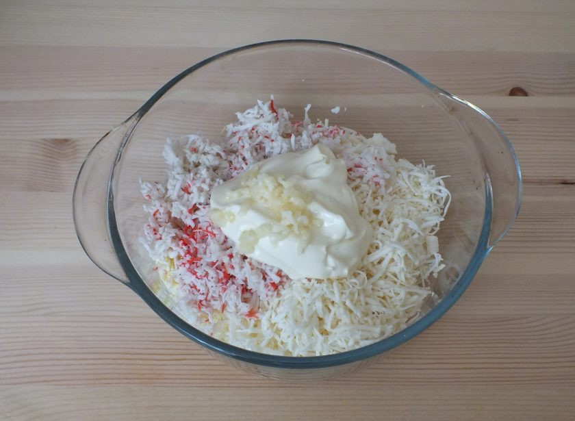1. Этап. Закуска новогодняя Мышки с крабовыми палочками: Добавьте к сыру с яйцами тертые крабовые палочки, майонез и измельченный чеснок. Перемешайте.