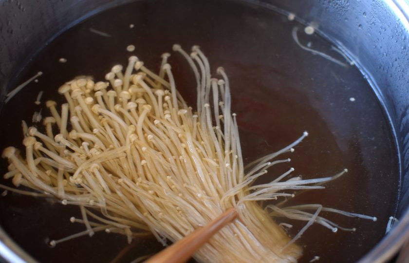 1. Этап. Грибная лапша на китайский манер: Бульон доведите до кипения, опустите в него пучок грибов эноки (или опят). Варите до полуготовности. Затем добавьте обжаренные грибы.