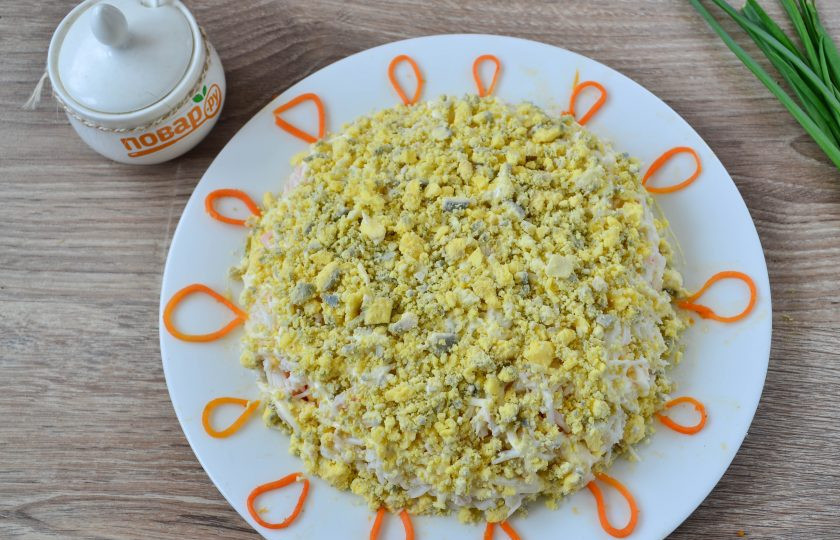 1. Этап. Салат Солнышко на Пасху: Желтки разомните в мелкую крошку, покройте ими салат сверху и по бокам. С помощью оставленной моркови сделайте лучики.