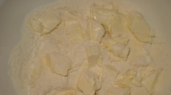 1. Этап. Орехи со сгущенкой: Первым делом приготовьте тесто для орешков. Для этого просейте несколько раз через сито пшеничную муку. Маргарин достаньте из холодильника и дайте ему постоять при комнатной температуре, чтобы он размягчился. Нарежьте маргарин на кусочки и положите его к муке. Перетрите муку с маргарином руками в крошку.