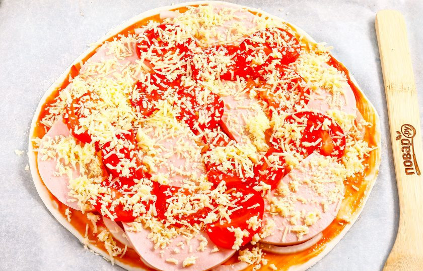 1. Этап. Пицца с колбасой из слоеного теста: Твердый сыр измельчите на терке с мелкими ячейками и присыпьте всю заготовку пиццы сверху сырной массой. Поместите в духовку на 10-15 минут, следя за поверхностью выпечки.