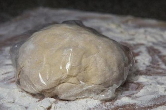 1. Этап. Печенье Хворост: Тесто нужно вымешать ложкой. Затем рабочую поверхность нужно щедро присыпать мукой, выложите на неё тесто, вымесите его руками. Вмешайте в тесто оставшуюся муку, заверните всё в пищевую плёнку и положите в холодильник на 15 минут.