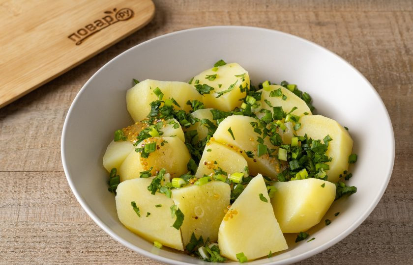 1. Этап. Горчичный картофель по-немецки: Слейте воду с готового картофеля, заправьте соусом, посыпьте зеленью и аккуратно перемешайте.