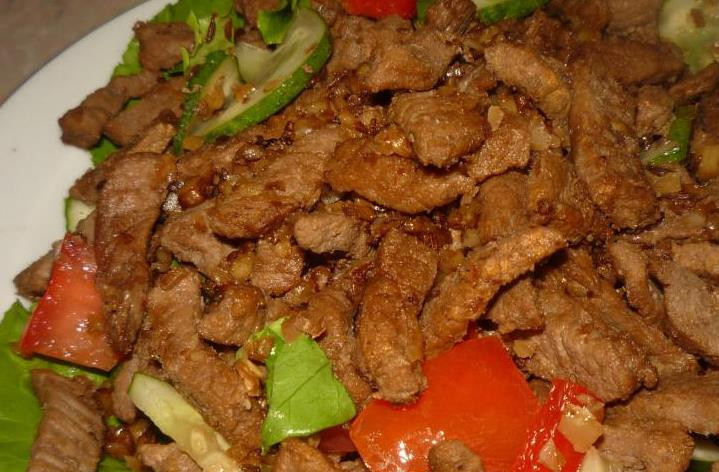 1. Этап. Салат с говядиной и орехами: Выкладываем мясо и слегка перемешиваем.