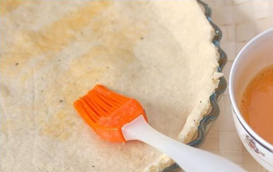 1. Этап. Печеночный пирог: 4. Достаньте форму с тестом из холодильника, сразу поставьте её в разогретую духовку. Выпекайте 15-20 минут при 180 градусах, после чего смажьте основу для пирога ½ яйца (которое предварительно взбейте, чтобы перемешались белок и желток). Продолжайте выпекать еще 5 минут. Яйцо при выпекании превратится в прочную пленку, которая изолирует тесто от начинки, чтобы оно не намокло. Сразу после выпекания аккуратно уберите выступающие из формы края теста.