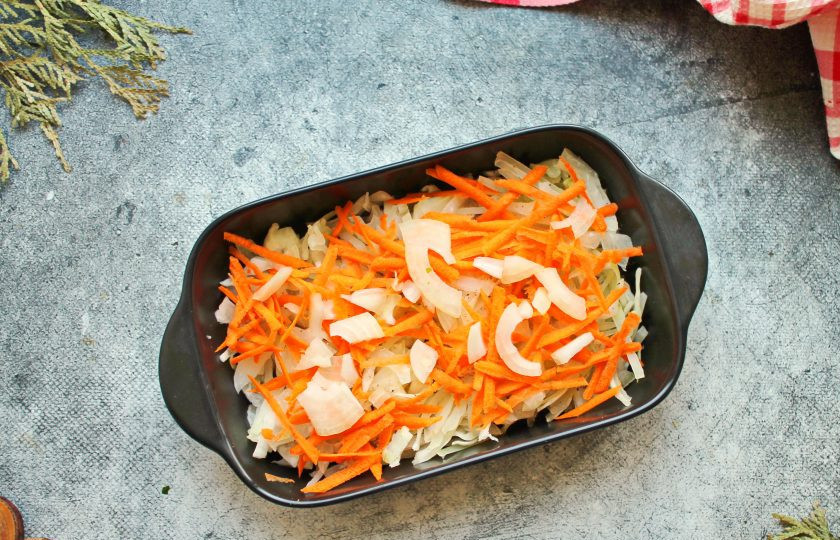 1. Этап. Треска с капустой: Репчатый лук порежьте, морковь натрите на средней или крупной терке. Овощи соедините и половину разложите на капусте равным слоем. Овощи немного посолите и поперчите.