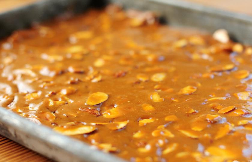 1. Этап. Миндальные конфеты: 3. Снять с огня и добавить нарезанный миндаль. Перемешать до однородной консистенции и вылить смесь на подготовленный противень. Разровнять поверхность шпателем. По мере охлаждения масса будет затвердевать.