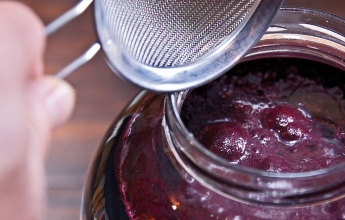 1. Этап. Вино из рябины: 10. Снимите крышки с банок, удалите пену. Перелейте в большую кастрюлю вино.