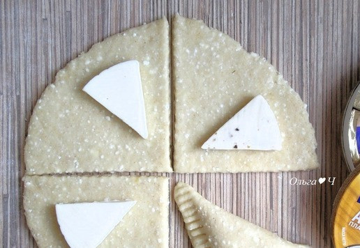 1. Этап. Творожные пирожки с сыром Ассорти: Сырные треугольники разрежьте вдоль пополам и выложите на каждую часть теста ближе к одной стороне. Накройте свободной частью теста, залепите края, дополнительно прижмите вилкой.