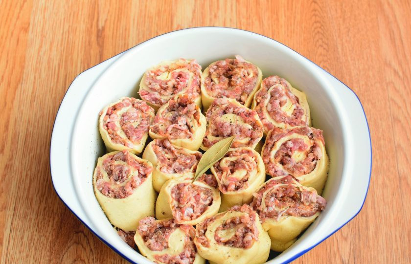 1. Этап. Ленивые пельмени в духовке: Хорошо смажьте форму сливочным маслом и довольно плотно расставьте кусочки рулета. При желании положите сверху лавровый листок.