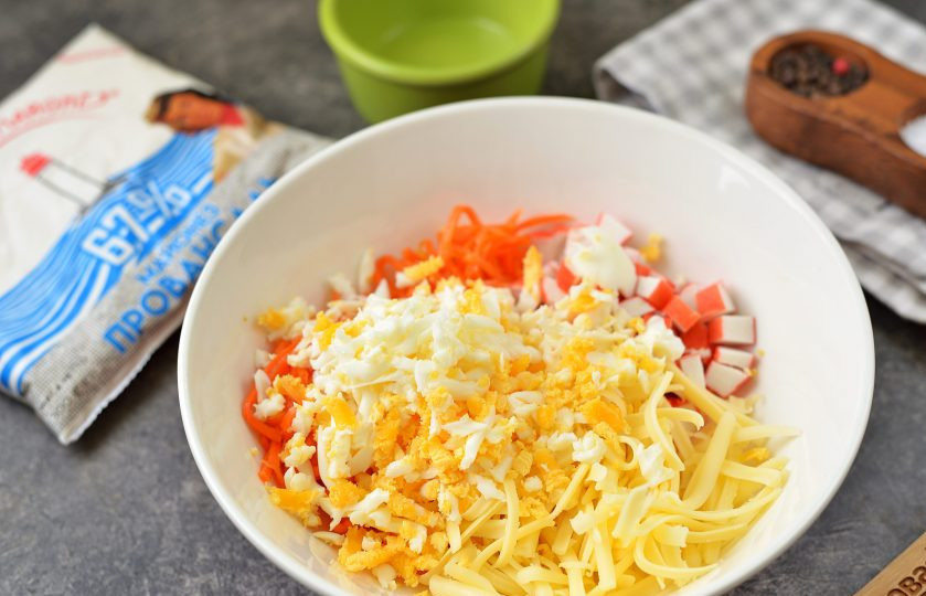 1. Этап. Салат из крабовых палочек, моркови по-корейски и сыра: Порубите куриное яйцо, переложите в миску вместе с тертым сыром.