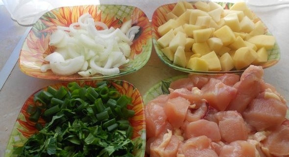 1. Этап. Куриная грудка в рукаве: Картофель почистите, помойте и нарежьте кубиками. Грудку промойте и нарубите порционными кусками. Лук почистите, нашинкуйте полукольцами. Зелень и зелёный лук помойте и измельчите.