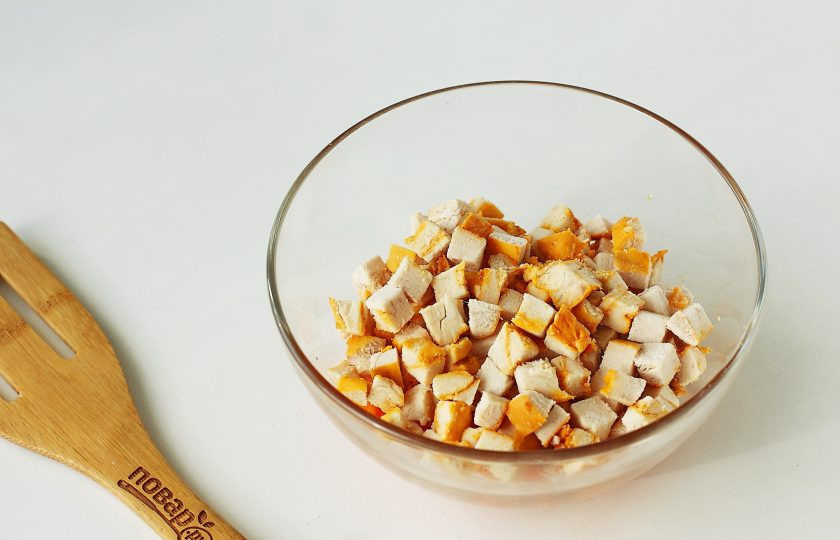 1. Этап. Салат с курицей и кириешками: Переложите обжаренную морковь в глубокую миску и добавьте сюда же нарезанную небольшими кубиками куриную грудку.