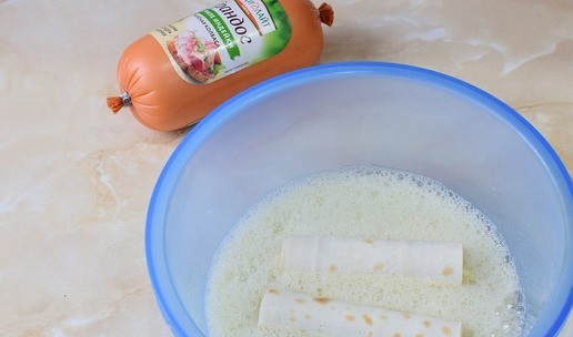 1. Этап. Трубочки с сыром и колбасой: В миске смешайте яйца с солью, окунайте трубочки и выкладывайте их на сковороду.