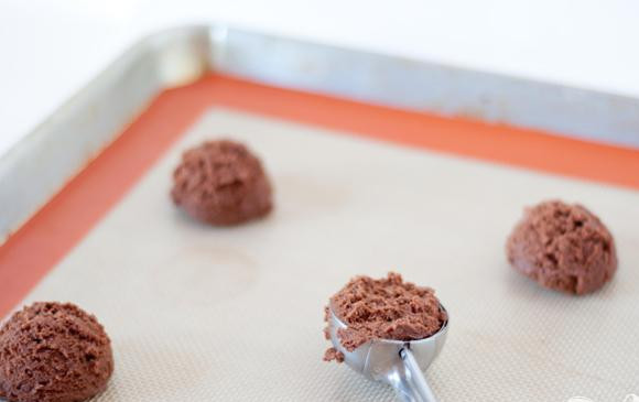 1. Этап. Шоколадное печенье с ванилью: 2. Разогреть духовку до 175 градусов. Выстелить противень силиконовым ковриком или пергаментной бумагой. Используя ложку или совок, выложить 1 столовую ложку шоколадного теста на противень, формируя круглую лепешку.