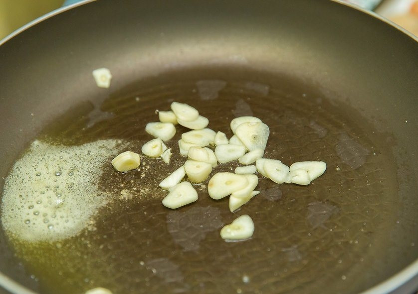 1. Этап. Морской гребешок: Порубите ножом чеснок и обжарьте на разогретом масле 1-2 минуты.