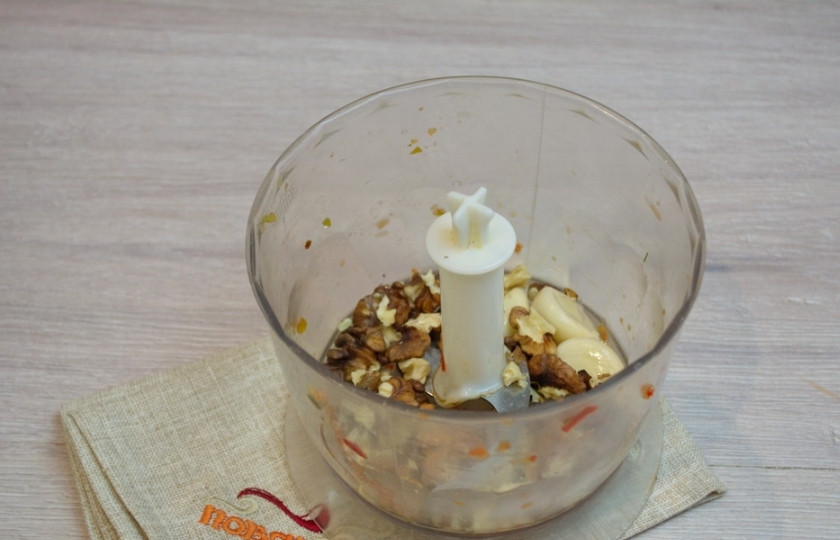 1. Этап. Аджика абхазская классическая: Полученную массу переложите в емкость. В чашу блендера закладываем очищенные ядра грецкого ореха. Аккуратно пересмотрите все ядрышки, чтобы не попались перепонки ореха. После измельчения их будет трудно извлечь и при поедании аджики можно сломать зубы. Орех измельчите до состояния пудры.