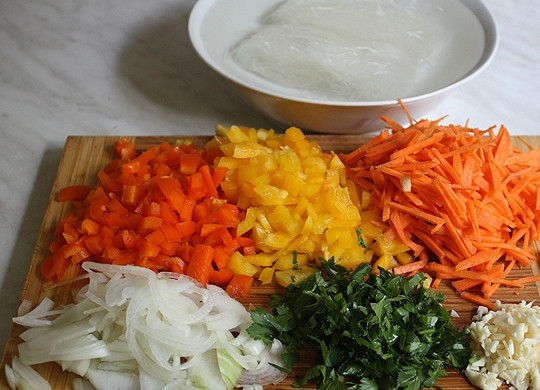 1. Этап. Фунчоза с болгарским перцем: Для начала измельчаем овощи: перец нарезаем кубиками, лук полукольцами, морковь соломкой, а чеснок и зелень просто измельчаем. Макароны заливаем кипятком и оставляем на 7 минут.