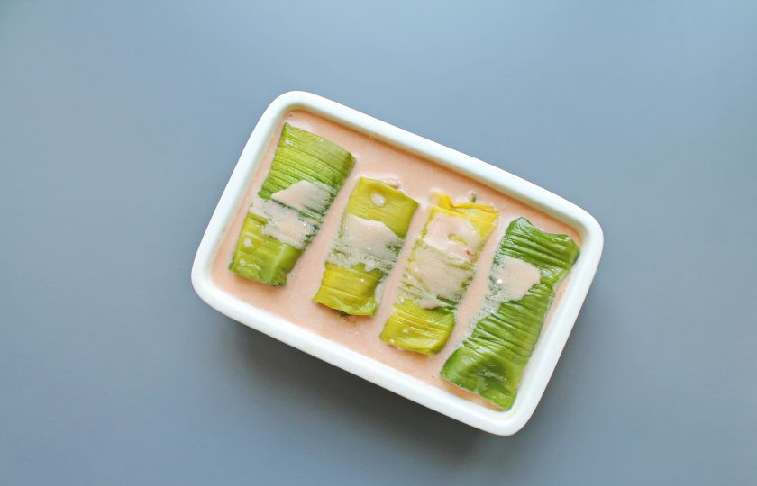 1. Этап. Голубцы в стеблях лука порея: Выложите голубцы в форму для запекания и залейте соусом.