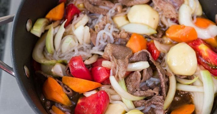 1. Этап. Говядина с лапшой Никудзяга: 2. Почистите и порежьте пополам картофель. Отправьте в сковороду картофель, нарезанные помидоры, лук, готовую лапшу, соевый соус, морковь и саке.