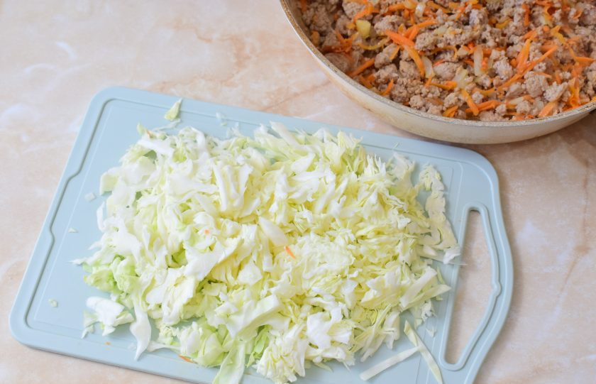 1. Этап. Бабушкины пуховые пирожки: Следом добавьте нашинкованную капусту. Перемешайте. Тушите на небольшом огне 15-20 минут. По вкусу добавьте соль и специи. При необходимости можно добавить немного воды. Если капуста свежая, то от неё будет достаточно сока для тушения. Готовую начинку остудите.