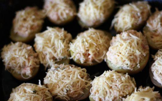 1. Этап. Запеченный картофель с начинкой: Начинку посолить и поперчить. Затем натереть сыр. Половину получившегося сыра добавить в начинку и снова все хорошенько перемешать. Начинить половинки картошин, сложить в плоскую, смазанную маслом, форму. Картошки с начинкой посыпать сыром и отправить в разогретую до 160 градусов духовку.