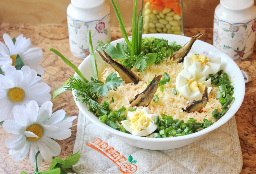 1. Этап. Салат Рыбки в пруду со шпротами: Украсьте салат. Шпроты воткните хвостиками вверх. Это будут выпрыгивающие из пруда рыбки. Выложите кувшинки из яиц. Украсьте салат зеленым луком, петрушкой и укропом.