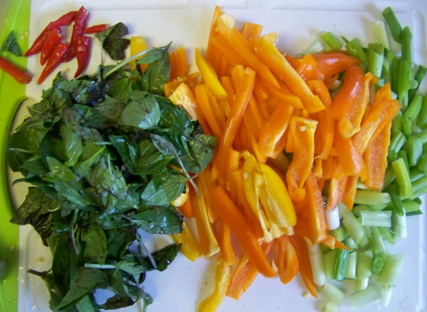 1. Этап. Свинина жареная с болгарским перцем: 4. Тем временем можно приступить к овощам. Данный рецепт приготовления жареной свинины с овощами предполагает использование сладкого и острого перцев, а также зеленого лука. Обязательным компонентом является и базилик. Перец очистить от хвостиков и семян, промыть и нарезать полосочками. Базилик вымыть и просушить. Лук также вымыть и нарезать небольшими кусочками.