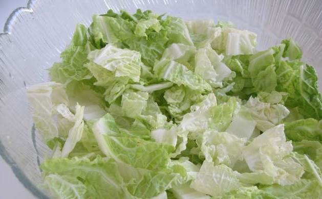 1. Этап. Салат из пекинской капусты с креветками: 2. Возьмите кочан пекинской капусты. Нарежьте его не слишком мелко. Толстые стебли капусты не добавляйте, они только испортят весь вкус салата. Выложите нашинкованную капусту в глубокую тарелку.